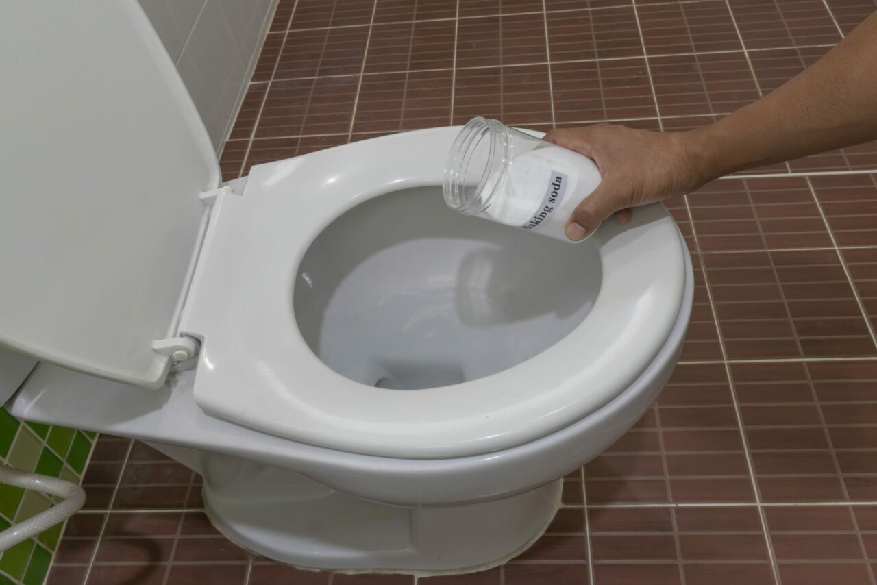 Man using baking soda to clean toilet bowl