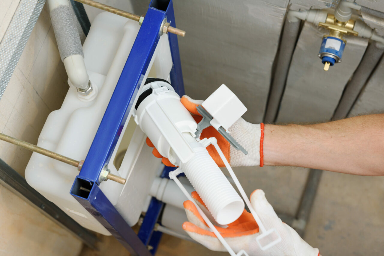 Plumber installing a toilet flush valve inside a tank — step-by-step repair process