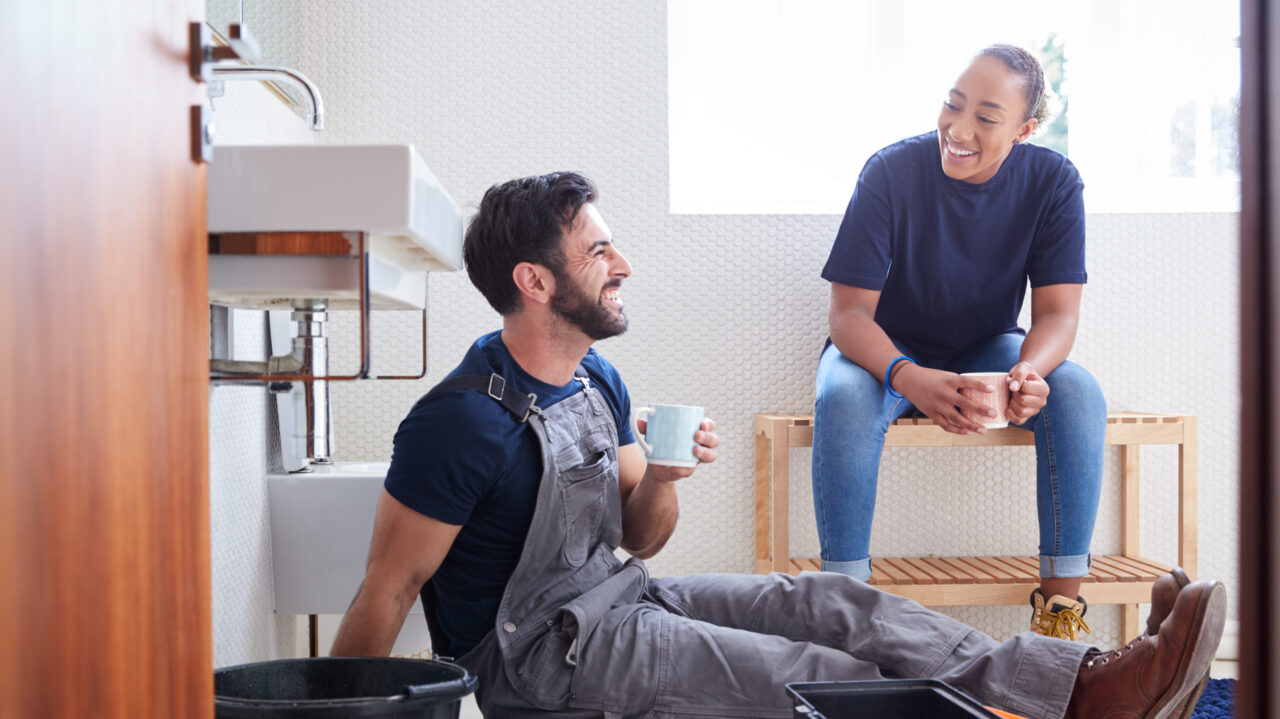 Two tradespeople take a coffee break while working on a bathroom renovation.