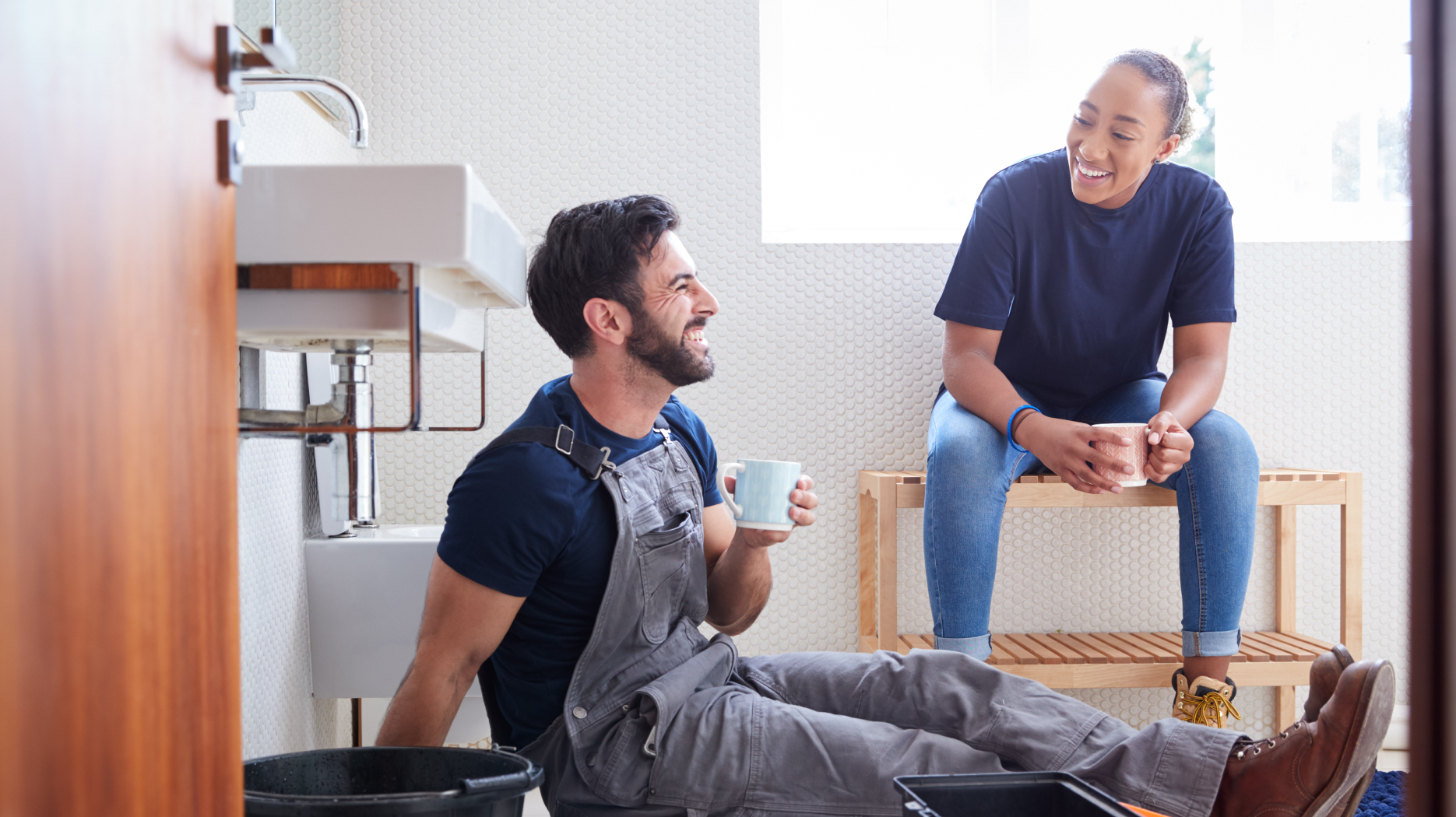 Two tradespeople take a coffee break while working on a bathroom renovation.
