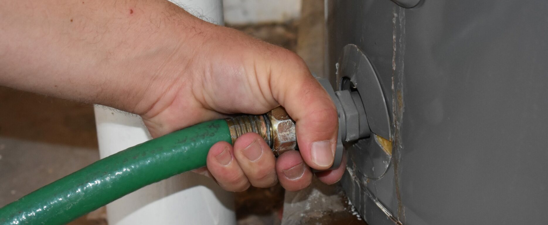 Hand Connecting Garden Hose to Drain the Water Heater