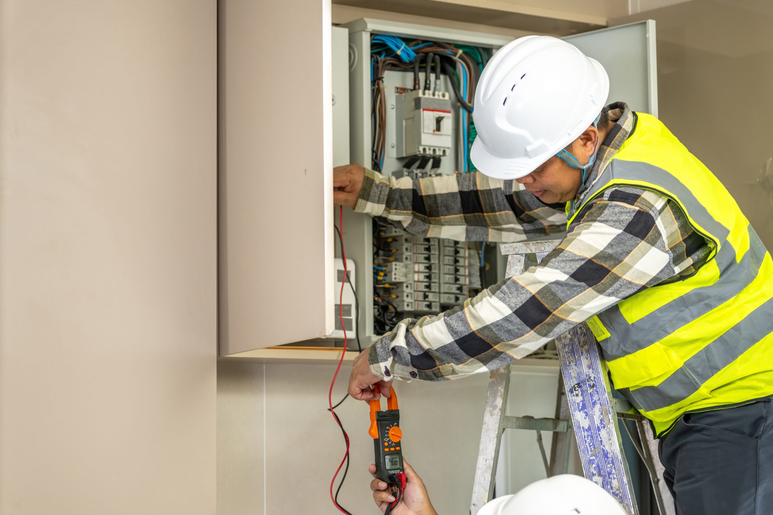 Skilled electrician worker inspecting electrical panel with multimeter testing wiring in residential building for safety and maintenance purposes.
