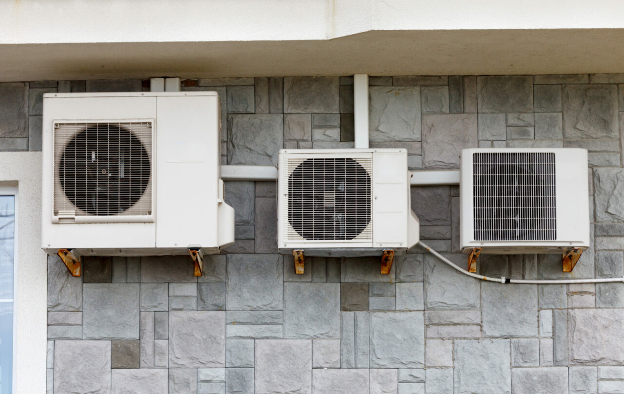 Three air conditioners of different sizes on the facade of the building
