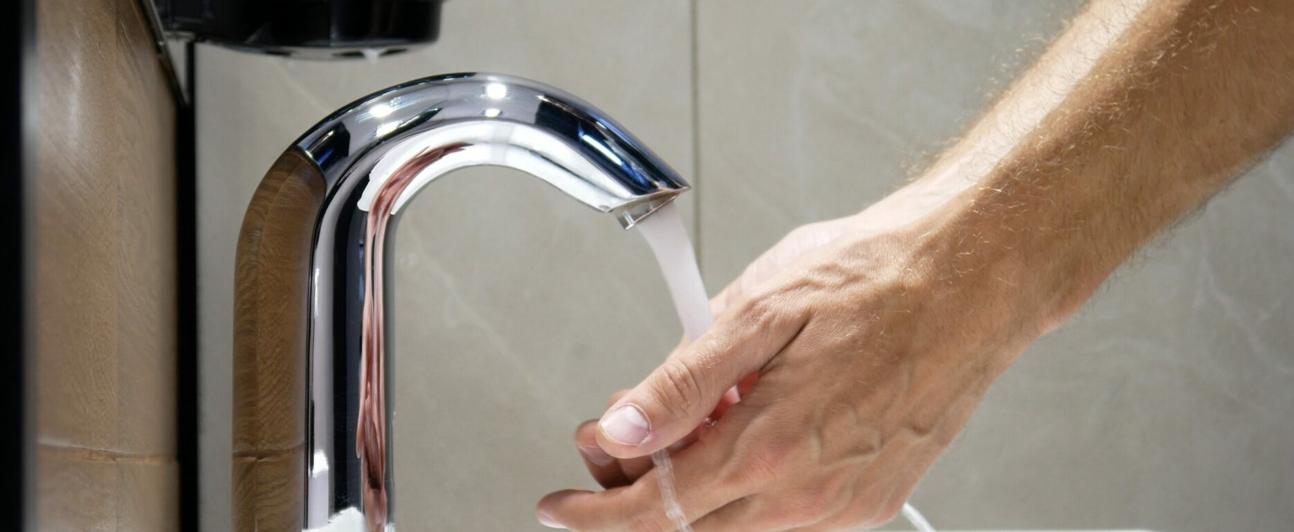 A man washes his hands using a touchless faucet