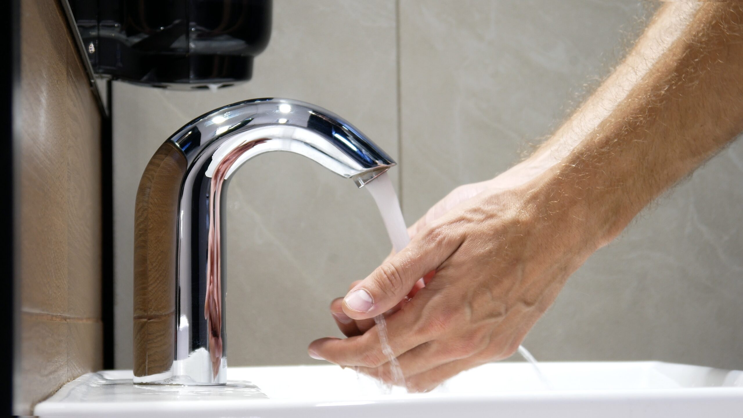 A man washes his hands using a touchless faucet