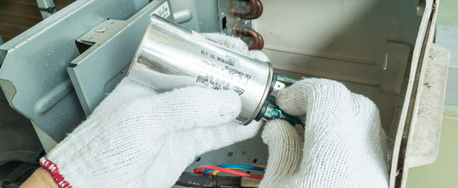 Technician installing new air conditioner capacitor