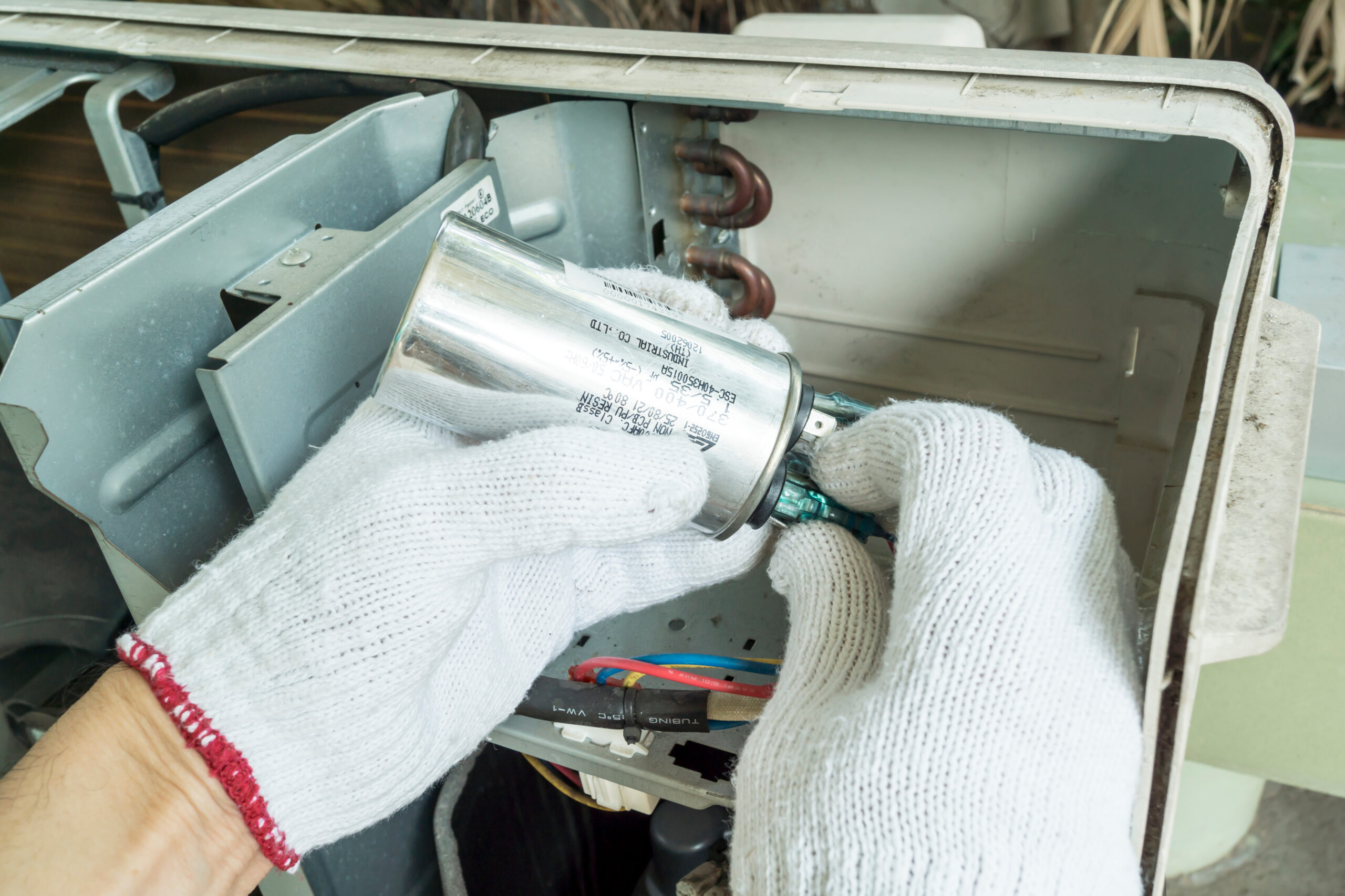 Technician installing new air conditioner capacitor