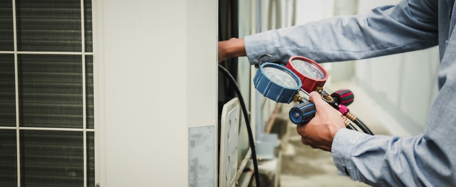technician is using a manifold gauge to check the refrigerant in the system