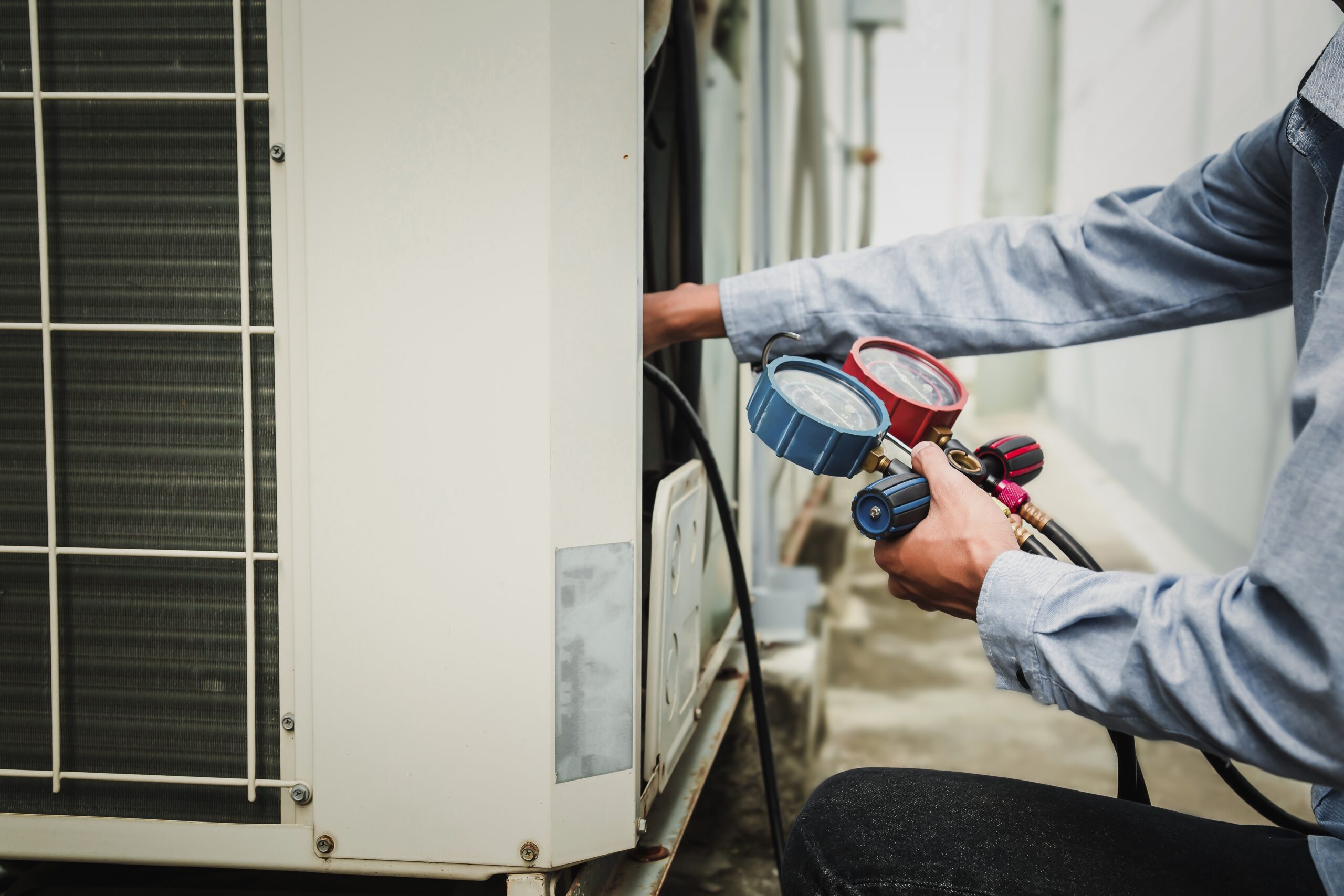 technician is using a manifold gauge to check the refrigerant in the system