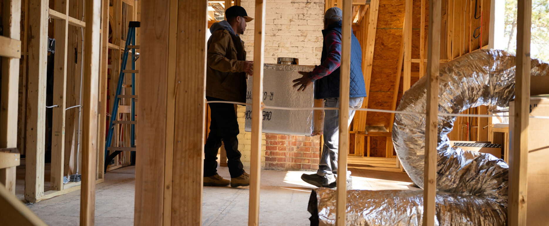 Tradesmen carrying an HVAC unit during installation