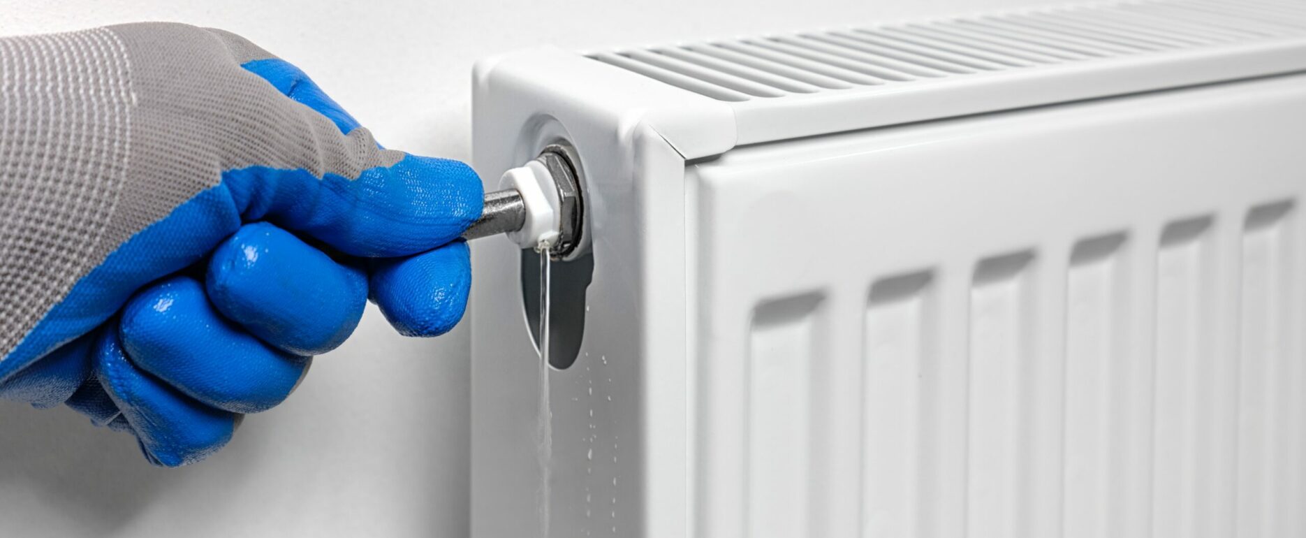 plumber uses a key to drain air, draining water and air from a radiator