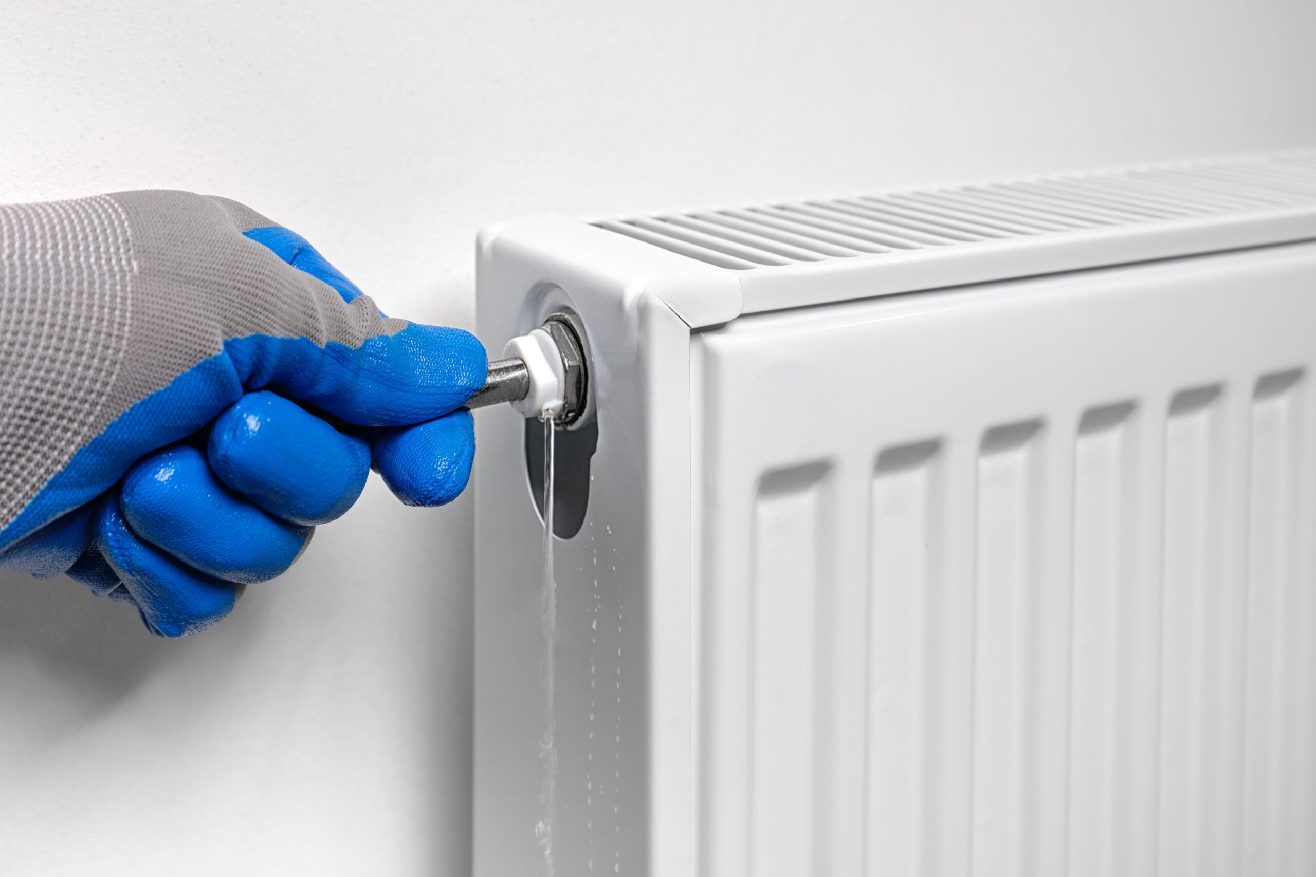 plumber uses a key to drain air, draining water and air from a radiator