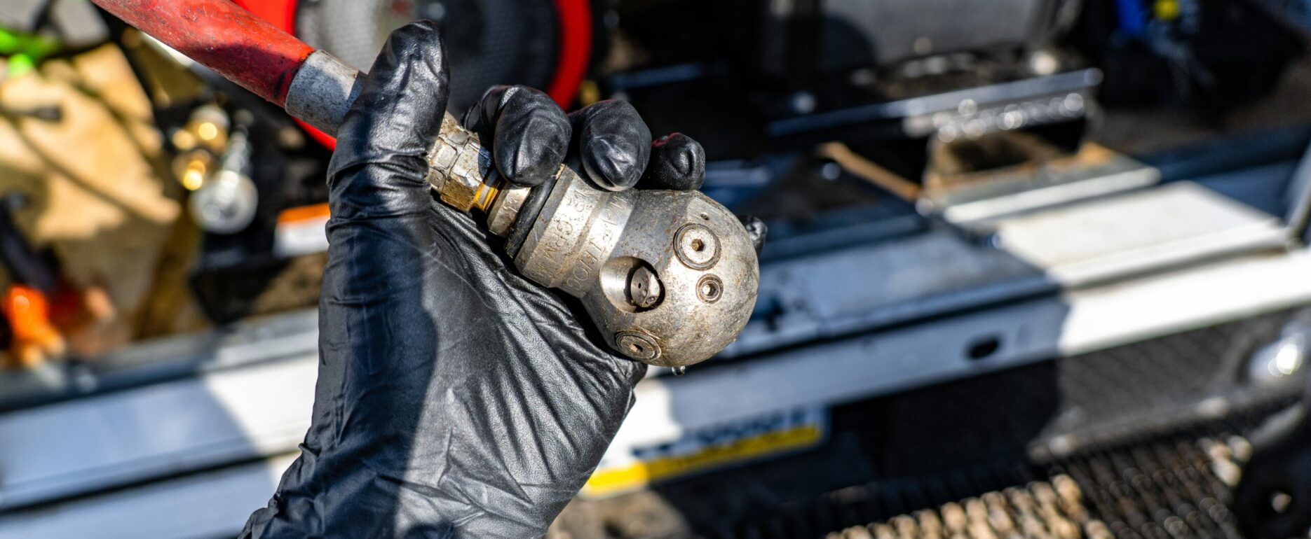 Plumber holding a jetter nozzle in front of a gas-powered sewer jetter unit