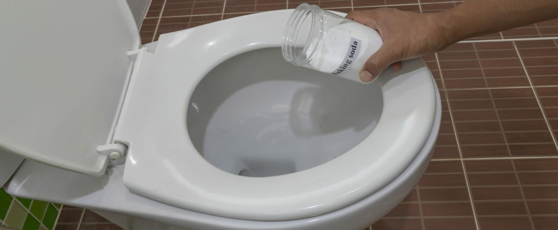 Man using baking soda to clean toilet bowl