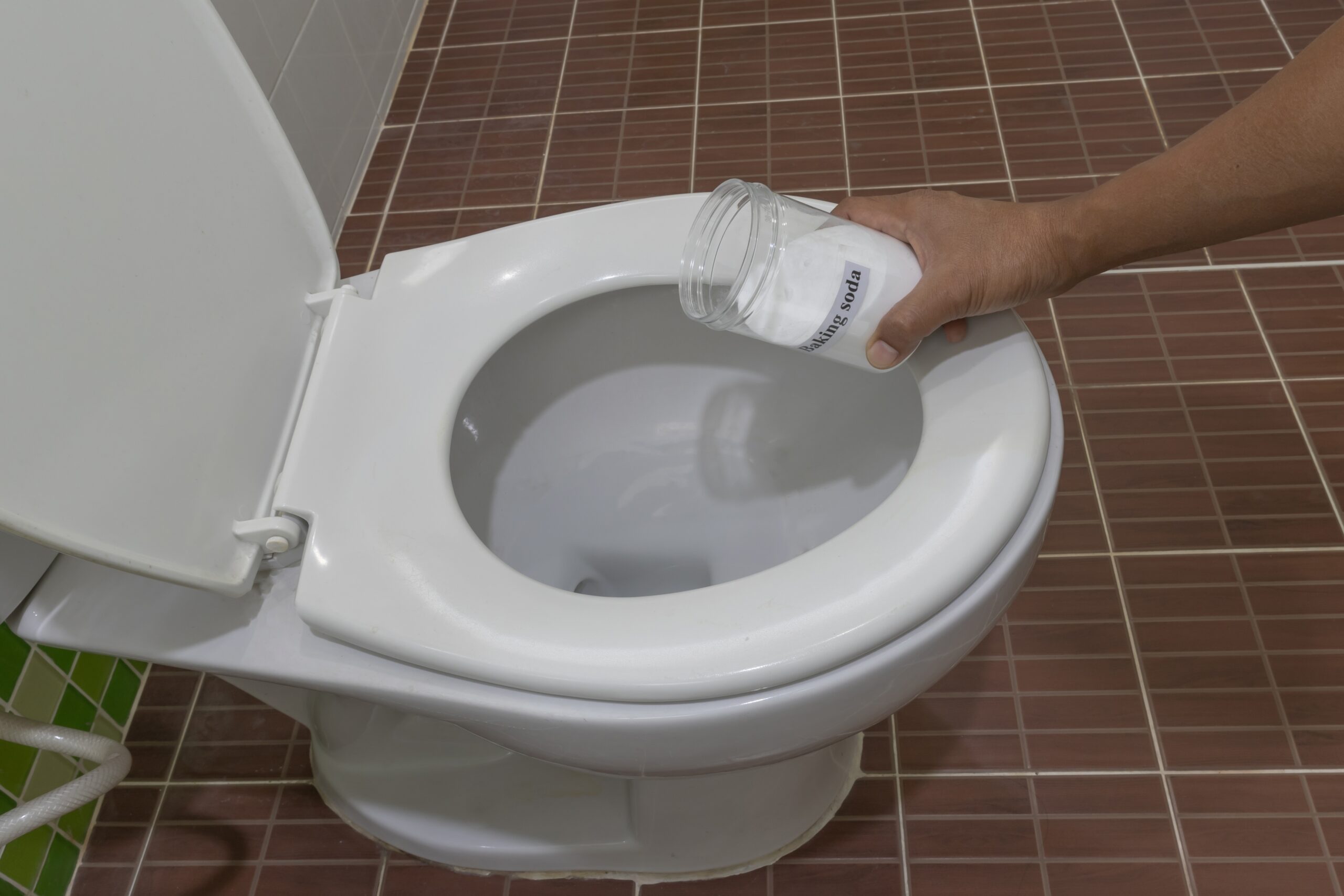 Man using baking soda to clean toilet bowl
